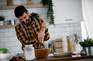 Mutfaktaki yakışıklı adamın portresi. Genç adam lezzetli yemekler hazırlıyor..