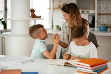 Anne oğullarıyla ödev yapıyor.
