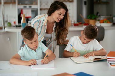 Anne oğullarıyla ödev yapıyor.