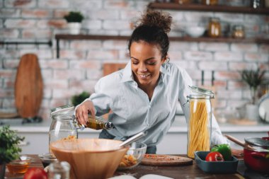 Güzel bir kadın yemek pişiriyor ve mutfakta eğleniyor. Kız mutfakta sağlıklı yemek pişiriyor..