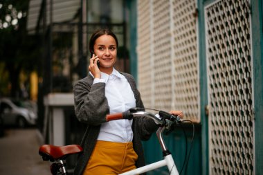 Akıllı telefon kullanan bisikletli genç bir kadın.