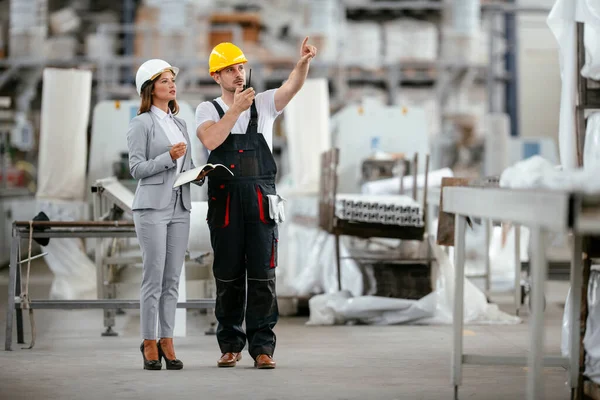 Müdür ve fabrika işçisi üretim hattında konuşuyor.