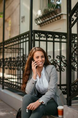 Kahve molasında telefon kullanan genç bir iş kadını.