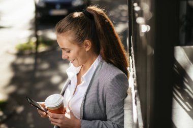 Kahve molasında telefon kullanan genç bir iş kadını.
