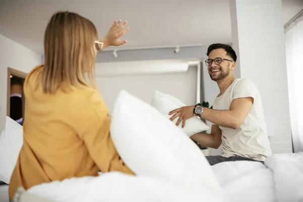 happy couple fighting with pillows at home