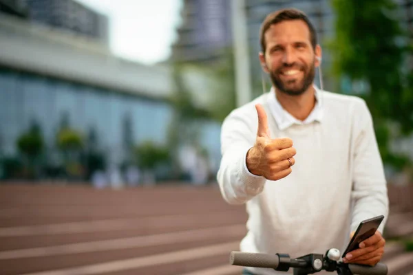 Businessman riding electric scooter. Man showing thumbs up.