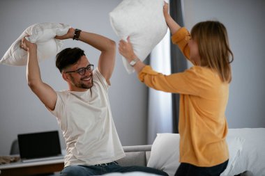 Mutlu çift evde yastıklarla kavga ediyor. 