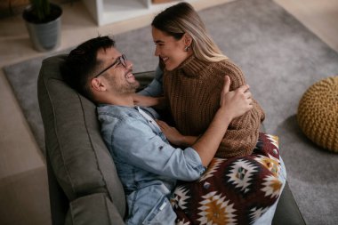 Genç adam ve kız arkadaşı oturma odasında kanepede.