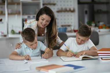 Anne oğullarıyla ödev yapıyor.
