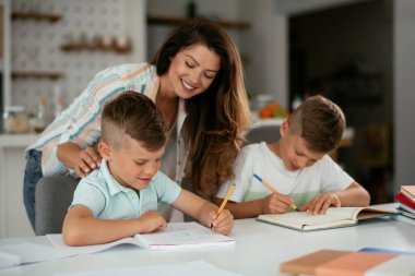 Anne oğullarıyla ödev yapıyor.