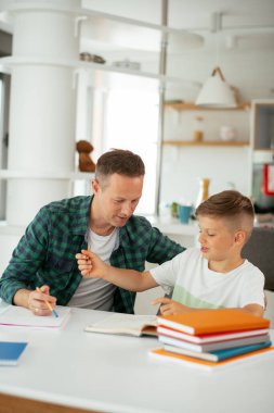 Baba, oğluna ev ödevinde yardım ediyor. Küçük çocuk evde öğreniyor..