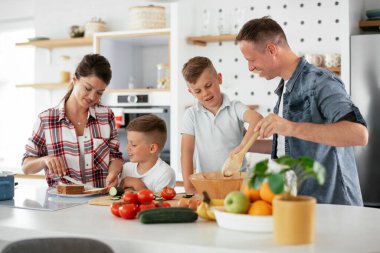 Genç mutlu aile evde sandviç yapıyor. Annem ve babam oğullarımla kahvaltı hazırlıyorlar..