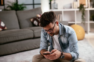 Giysilerini seyahat çantasına koyan gülümseyen genç adam. Yolculuğa hazırlanan adam.