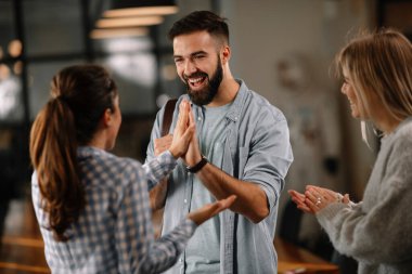 Modern açık uzay ofisinde sıradan iş adamlarından oluşan bir grup. İş kadınları ve işadamları yeni proje hakkında konuşuyor.