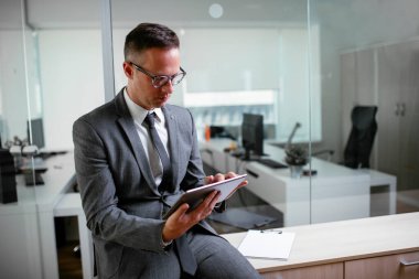 Ofiste çalışan yakışıklı bir iş adamı. Genç işadamı tableti kullanıyor..