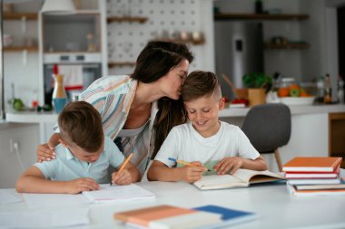 Anne oğullarıyla ödev yapıyor.