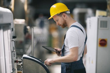 Üretim hattındaki fabrika işçisi. Fabrikada çalışan kasklı bir adam..