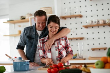 Genç çift evde kahvaltı hazırlıyor. Sevgi dolu çift mutfakta sandviç yiyor..