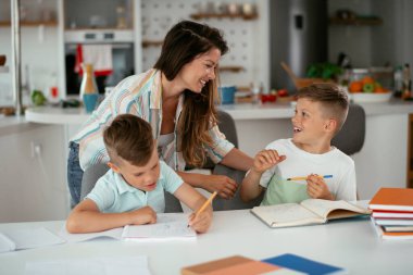 Anne oğullarıyla ödev yapıyor.