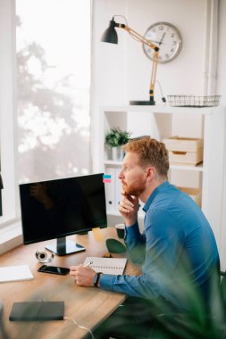 Ofiste çalışan bir iş adamı. Kızıl adam işyerinde oturuyor..