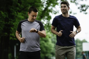 Gençler yarış pistinde antrenman yapıyor. İki genç arkadaş atletizm pistinde koşuyor.