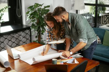 Tasarımcı, ortaklarına proje hakkında yeni fikirler veriyor. İşadamları ofiste yeni bir iş projesi üzerinde tartışıyorlar.