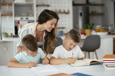 Anne oğullarıyla ödev yapıyor.