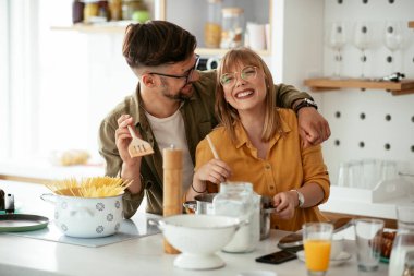 Karı koca mutfakta. Genç çift evde lezzetli yemekler hazırlıyor..