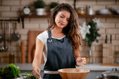 Gülümseyen kadın mutfakta yemek yapıyor.