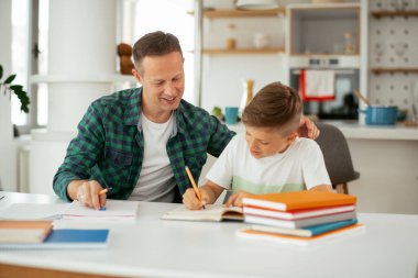 Baba, oğluna ev ödevinde yardım ediyor. Küçük çocuk evde öğreniyor..