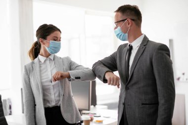 Ofiste tıbbi maskeli bir iş adamı ve iş kadını var. Covid-19 saatinde selamlar..