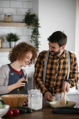 Erkek arkadaş ve kız arkadaş evde lezzetli yemekler yapıyor. Aşkın çifti mutfakta yemek pişiriyor.