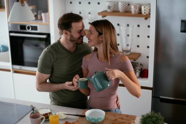 Sevgili çift kahvaltı hazırlarken kahve içiyorlar..