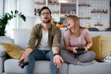 Çift evdeki kanepede oyun oynuyor.