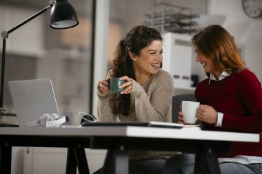 Açık uzay ofisinde konuşan ve gülen mutlu iş kadınları
