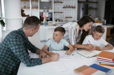 Ebeveynler çocuklara ev ödevlerinde yardım ediyorlar. Küçük çocuklar evde öğreniyor..