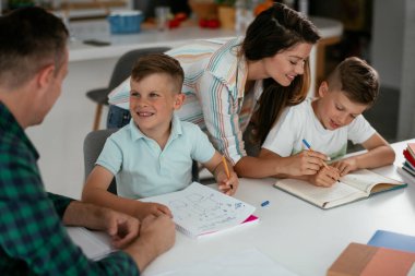 Anne ve baba oğullarına ev ödevlerinde yardım ederler.