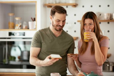 Genç çift evde sandviç yapıyor. Sevgi dolu çift mutfakta eğleniyor..
