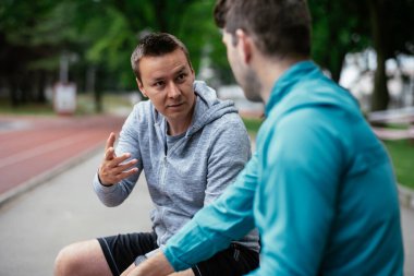 Koşmaktan istirahat eden zinde genç adamlar. Dışarıda antrenman yapan iki arkadaş..