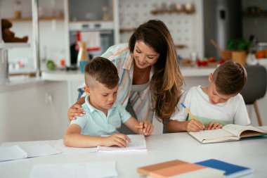 Anne oğullarıyla ödev yapıyor.
