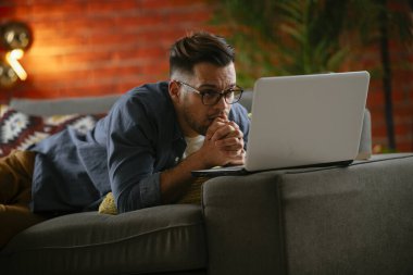 Evdeki dizüstü bilgisayarda dizi izleyen bir adam..