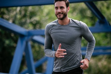 Genç adam şehirde koşuyor. Dışarıda antrenman yapan mutlu bir sporcu.