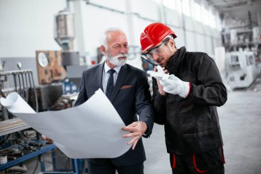 İş arkadaşları birlikte çalışıyor. Fabrikada mimar ve işçi..