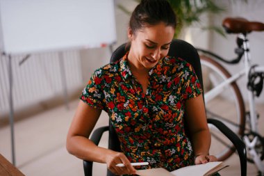 Genç ve güzel bayan girişimci iş yerinde not alıyor. 