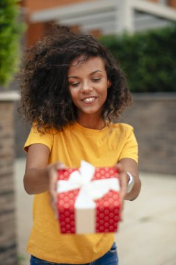 Genç Afrikalı bir kadın hediye veriyor.