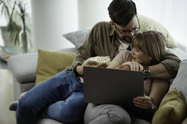 Dizüstü bilgisayarda film izleyen genç bir çift. Sevgili çift evde eğleniyor..