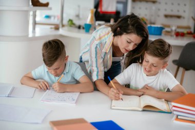 Anne oğullarıyla ödev yapıyor.