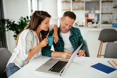 Evde dizüstü bilgisayar kullanan mutlu genç çift.