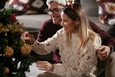 Genç çift Noel ağacı süslüyorlar.