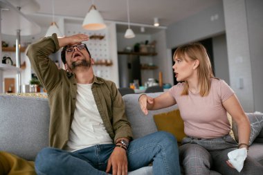 Erkek arkadaşı ve kız arkadaşı kanepede tartışıyor. Kızgın kadın erkek arkadaşına bağırıyor..